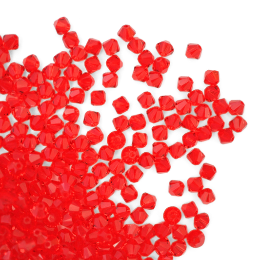 Austrian crystal 5328 bicone beads in the color Light Siam spilling out onto a white background.