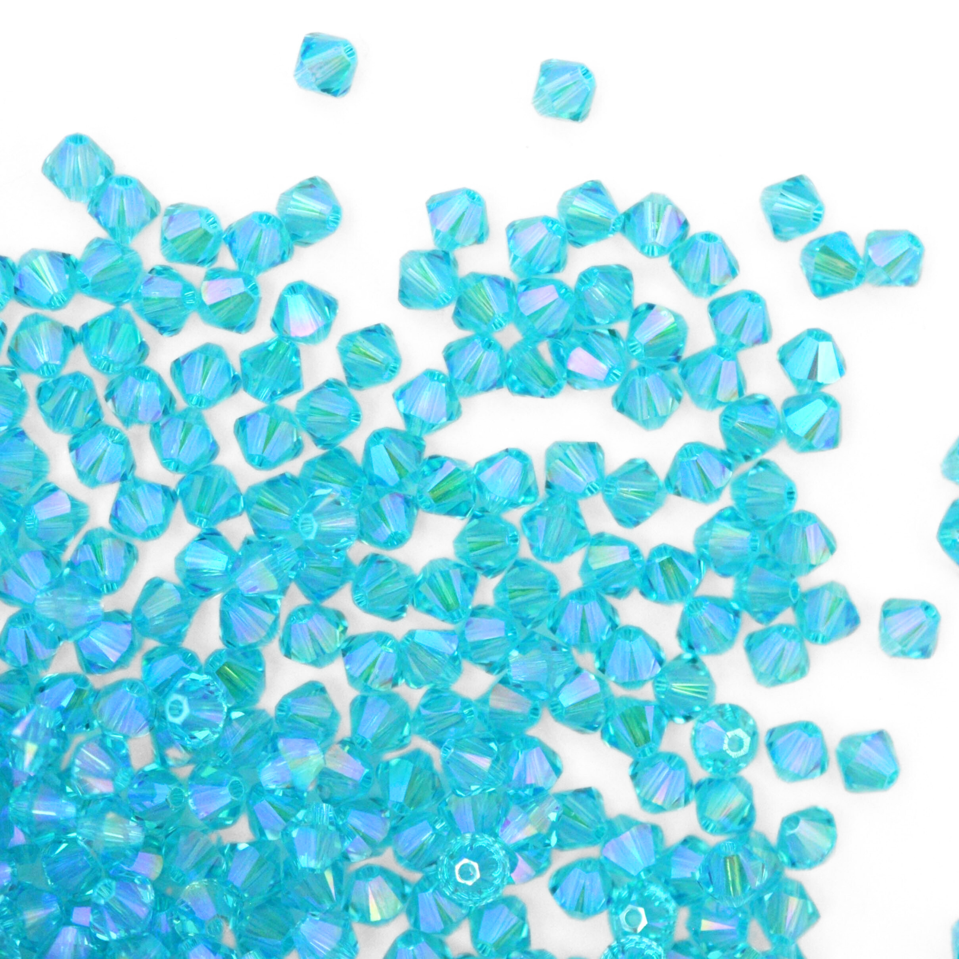 Austrian crystal 5328 bicone beads in the color Light Turquoise Shimmer 2X spilling out onto a white background.