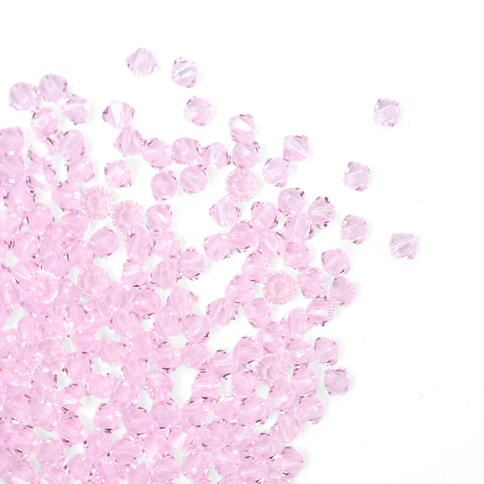 Austrian crystal 5328 bicone beads in the color Rosaline spilling out onto a white background.
