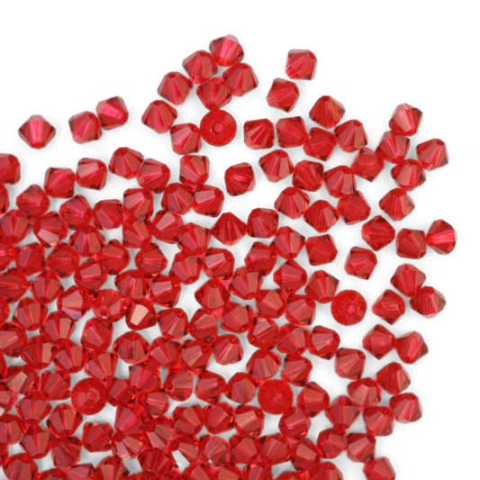 Austrian crystal 5328 bicone beads in the color Scarlet spilling out onto a white background.