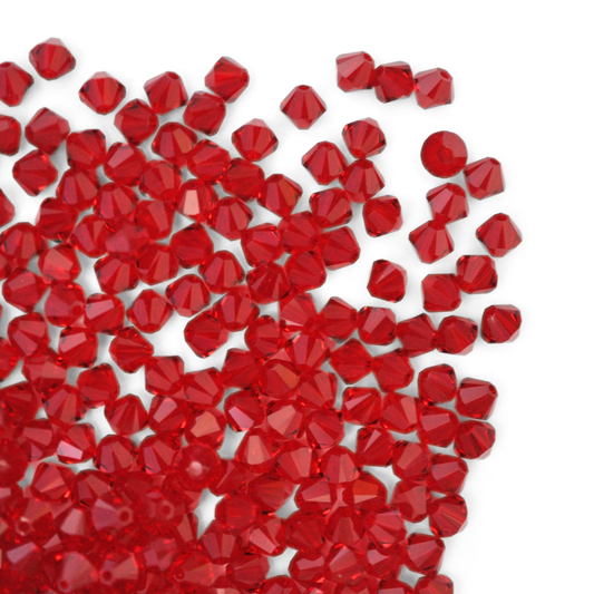 Austrian crystal 5328 bicone beads in the color Siam spilling out onto a white background.