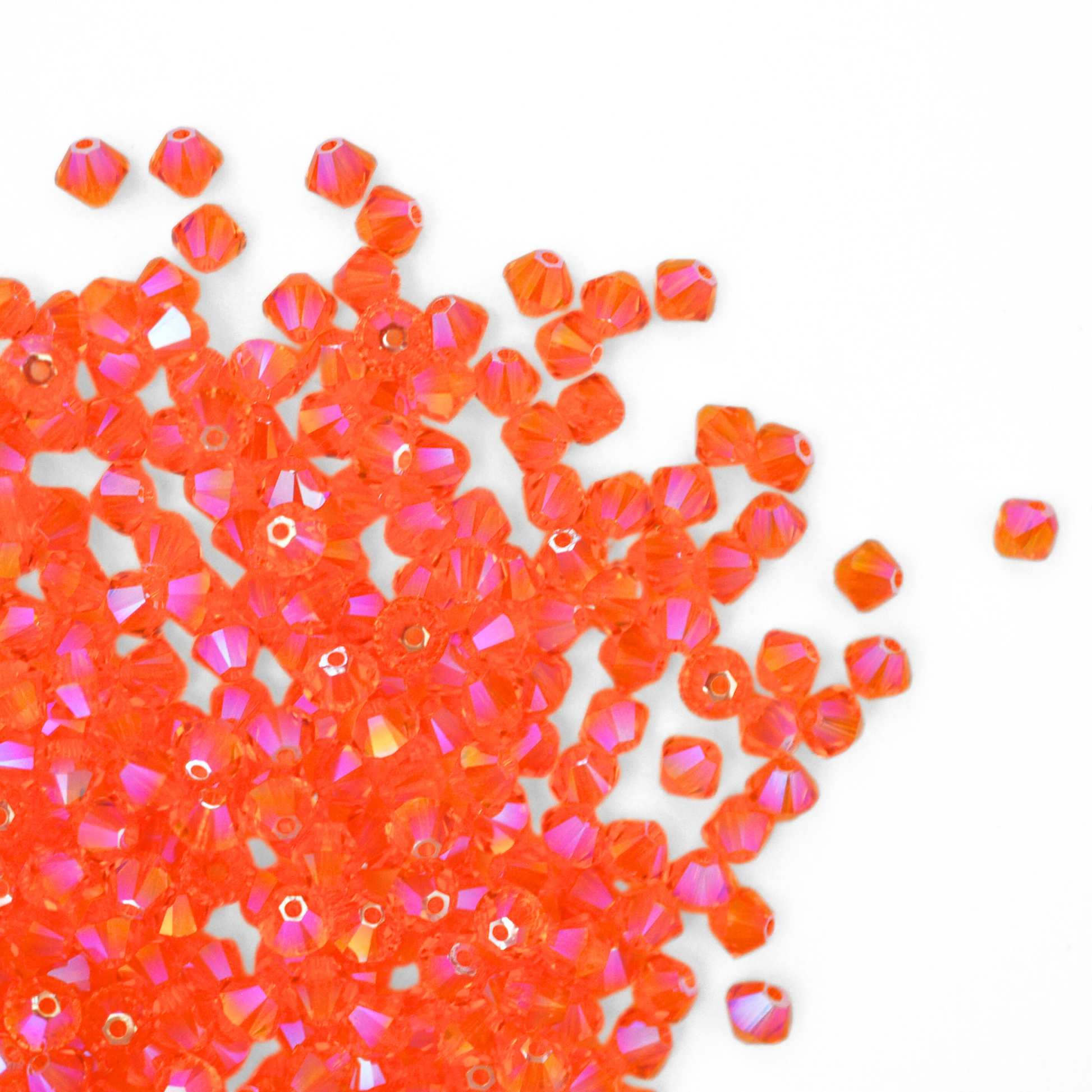 Austrian crystal 5328 bicone beads in the color Sun Shimmer 2X spilling out onto a white background.