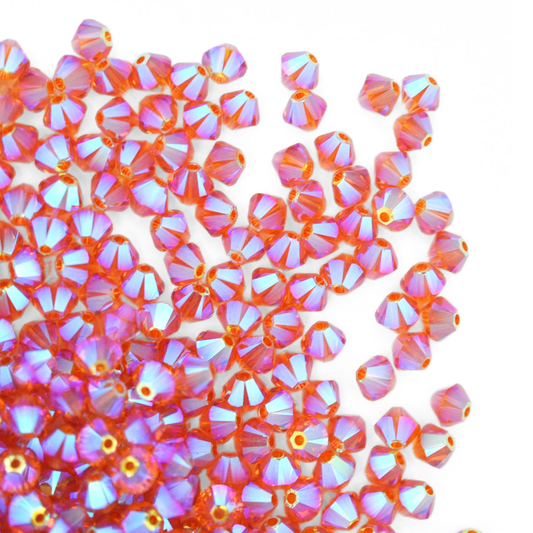 Austrian crystal 5328 bicone beads in the color Topaz AB2X spilling out onto a white background.