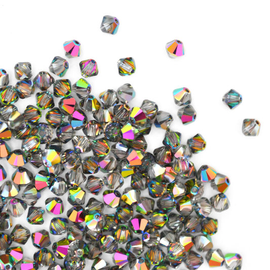 Austrian crystal 5328 bicone beads in the color Vitrail Medium spilling out onto a white background.