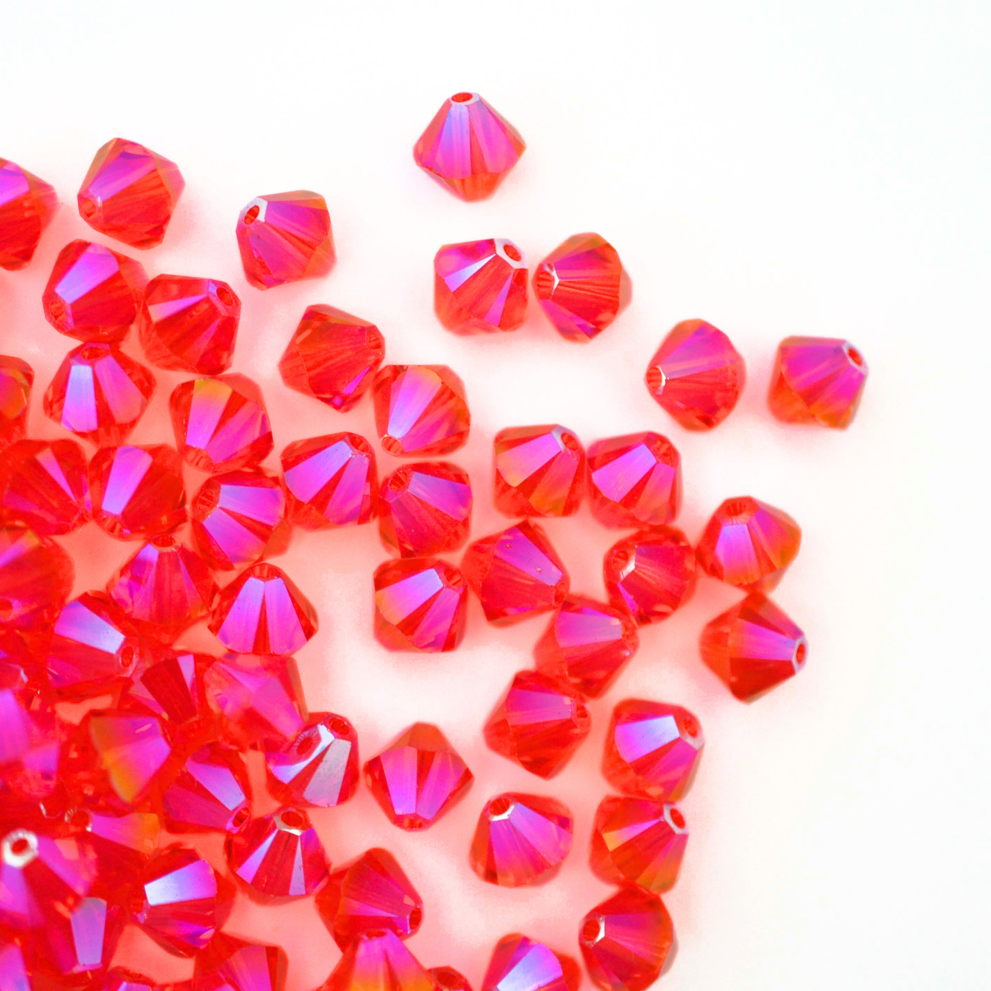 Austrian crystal 5328 bicone beads in the color Hyacinth Shimmer 2X spilling out onto a white background.