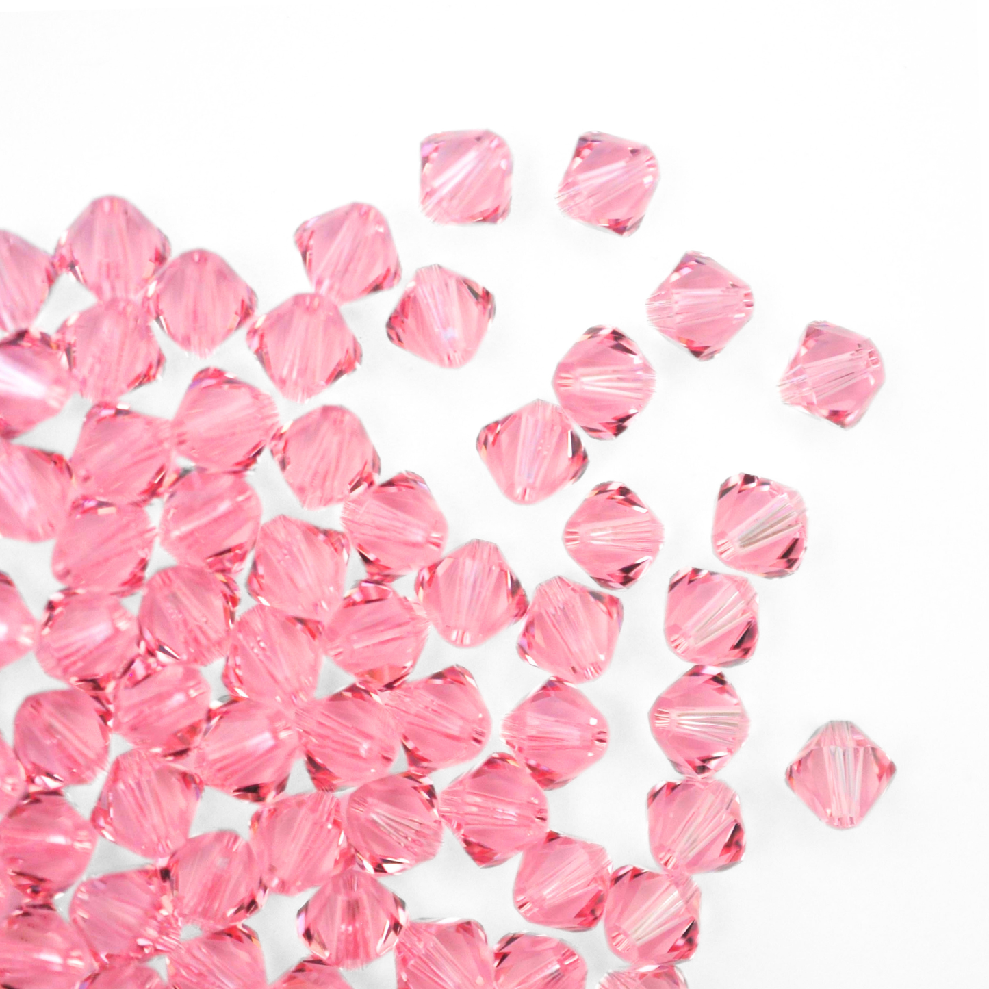 Austrian crystal 5328 bicone beads in the color Light Rose spilling out onto a white background.