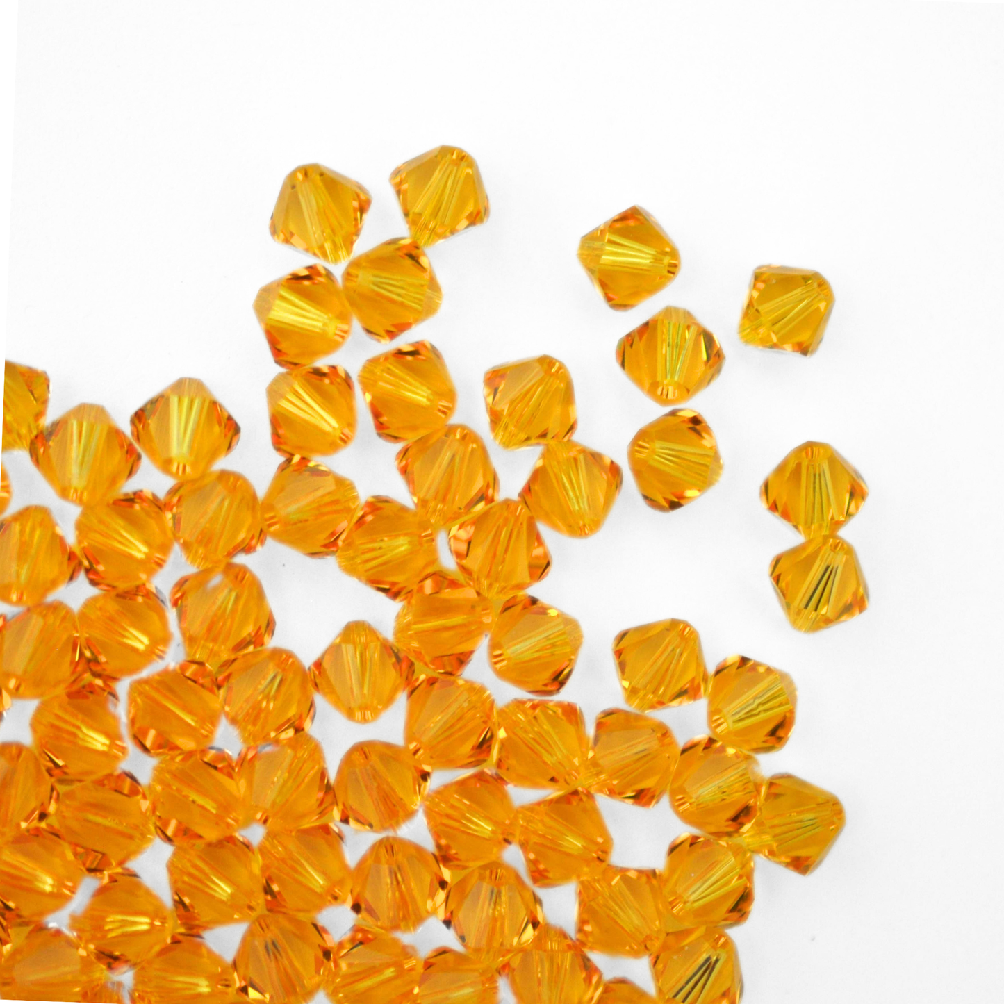 Austrian crystal 5328 bicone beads in the color Sunflower spilling out onto a white background.