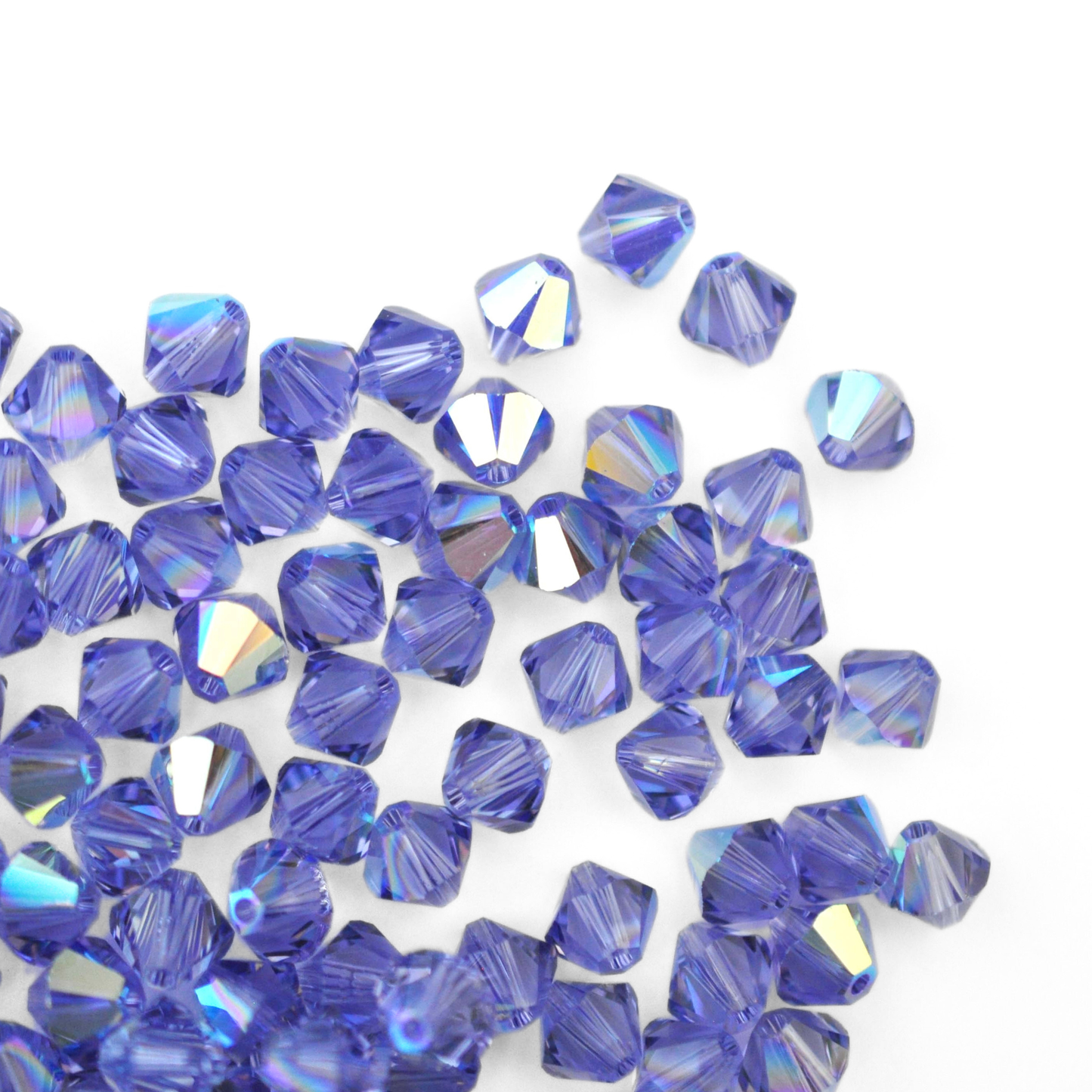 Austrian crystal 5328 bicone beads in the color Tanzanite AB spilling out onto a white background.