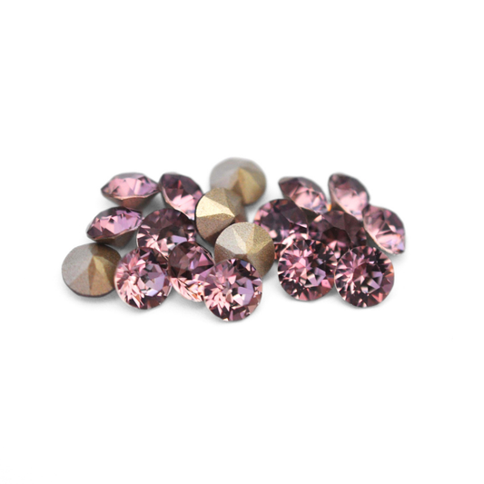 Round faceted Austrian crystal rhinestones in the color Antique Pink displayed on a white background