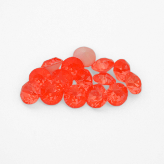 Round faceted Austrian crystal rhinestones in the color Electric Orange Ignite displayed on a white background