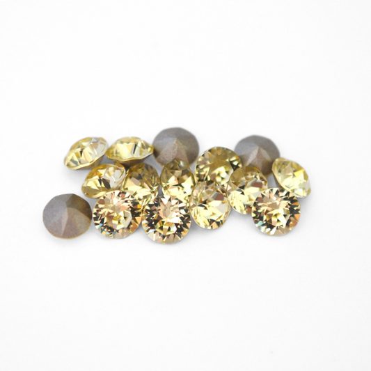 Round faceted Austrian crystal rhinestones in the color Jonquil displayed on a white background
