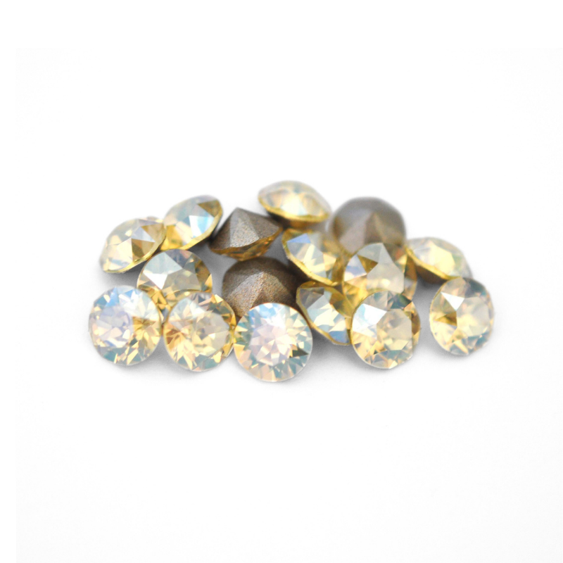Round faceted Austrian crystal rhinestones in the color Jonquil Moonlight displayed on a white background