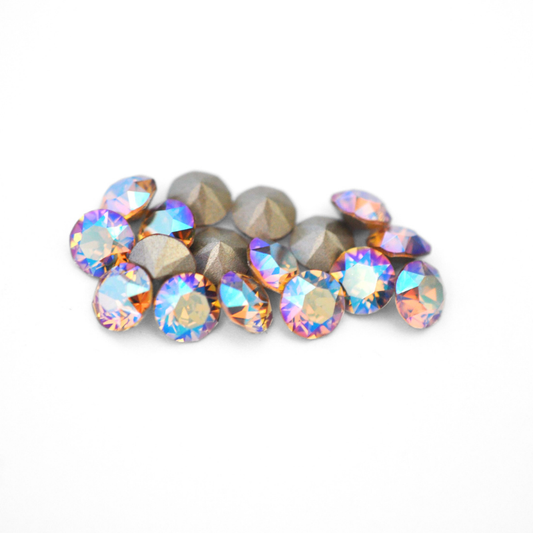 Round faceted Austrian crystal rhinestones in the color Light Colorado Topaz Shimmer displayed on a white background