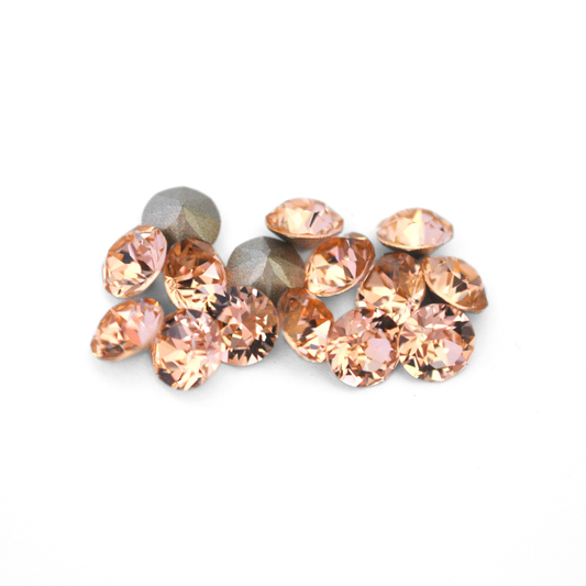 Round faceted Austrian crystal rhinestones in the color Light Peach displayed on a white background