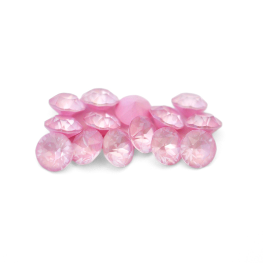 Round faceted Austrian crystal rhinestones in the color Soft Rose Ignite displayed on a white background
