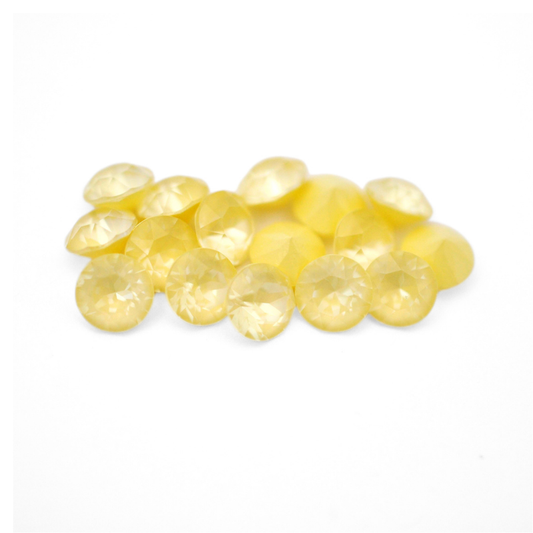Round faceted Austrian crystal rhinestones in the color Soft Yellow Ignite displayed on a white background