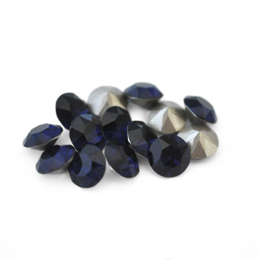 Round faceted Austrian crystal rhinestones in the color Dark Indigo displayed on a white background.