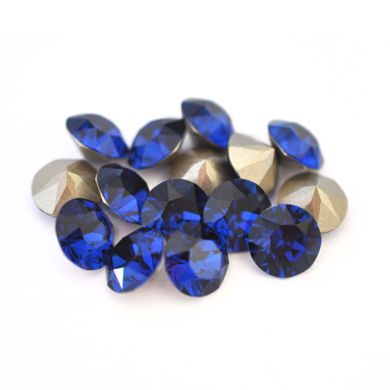 Round faceted Austrian crystal rhinestones in the color Dark Sapphire displayed on a white background.