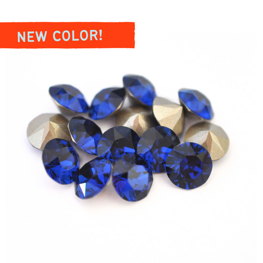 Round faceted Austrian crystal rhinestones in the color Dark Sapphire displayed on a white background.