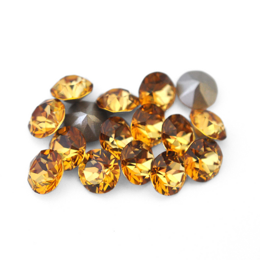 Round faceted Austrian crystal rhinestones in the color Golden Topaz displayed on a white background.