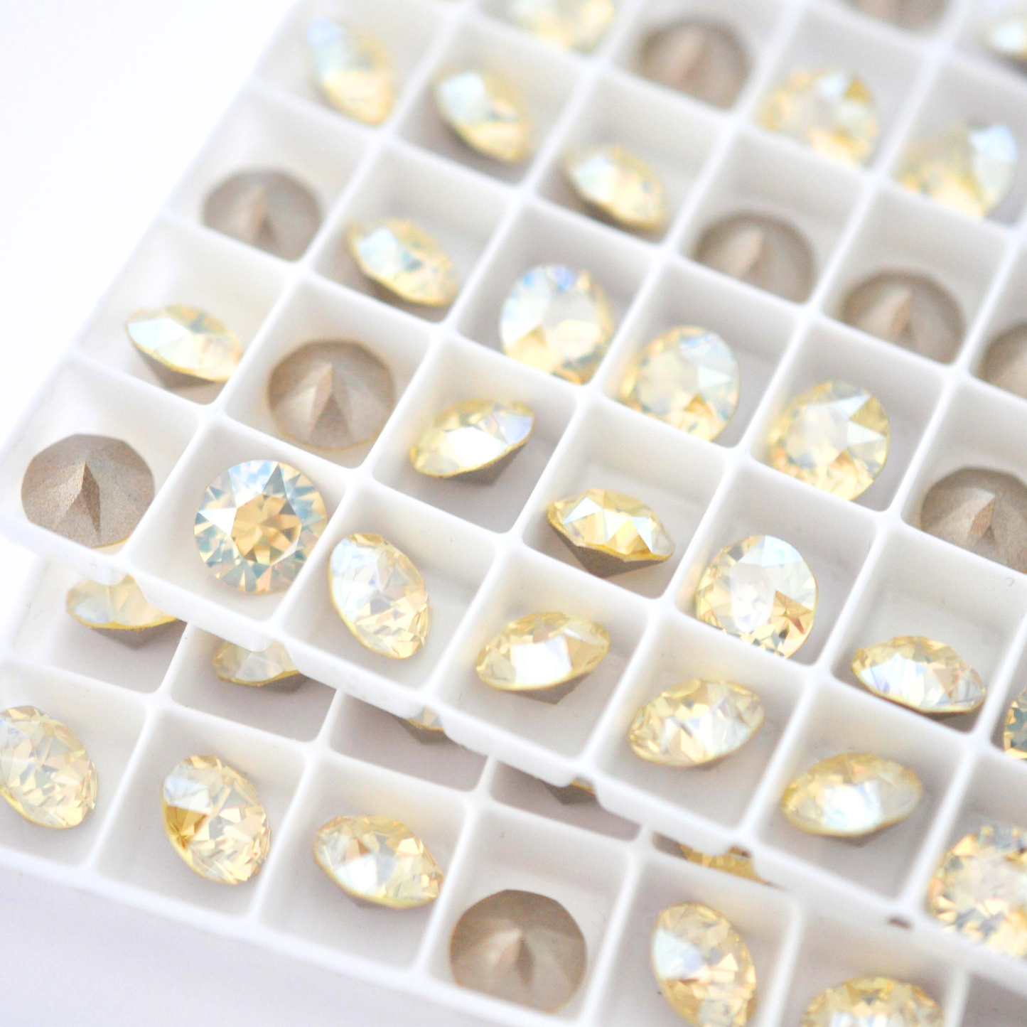 Round faceted Austrian crystal rhinestones in the color Jonquil Moonlight in a tray.