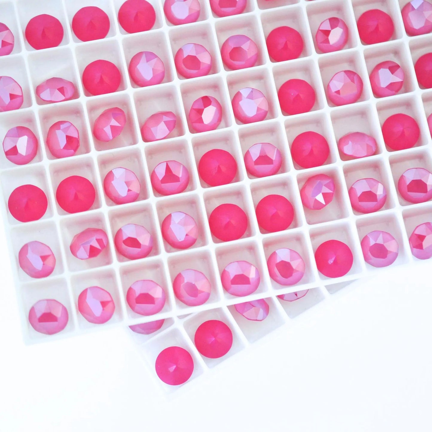 Round faceted Austrian crystal rhinestones in the color Peony Pink displayed in a tray.