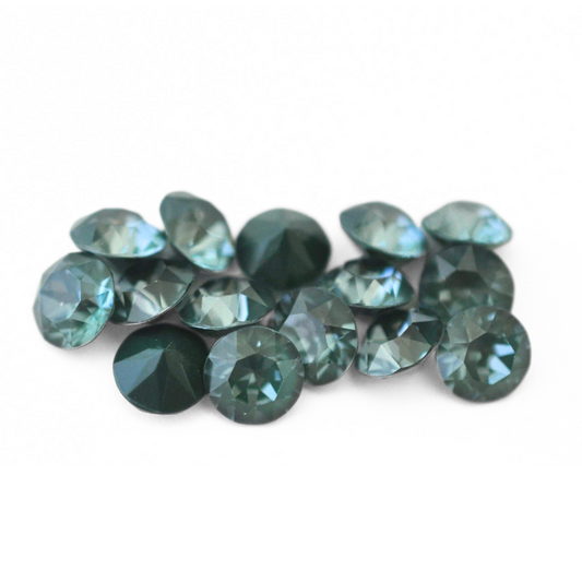 Round faceted Austrian crystal rhinestones in the color Pine Green Ignite displayed on a white background.