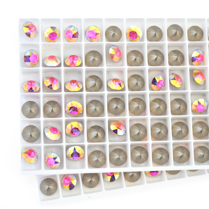 Round faceted Austrian crystal rhinestones in the color Rose Transmission displayed on a tray.