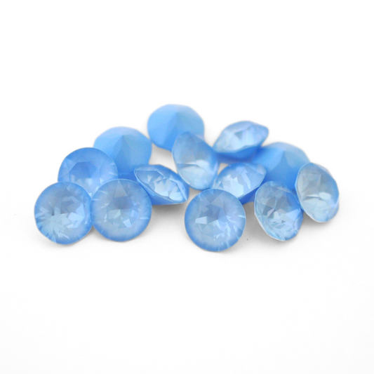Round faceted Austrian crystal rhinestones in the color Sky Ignite displayed on a white background.