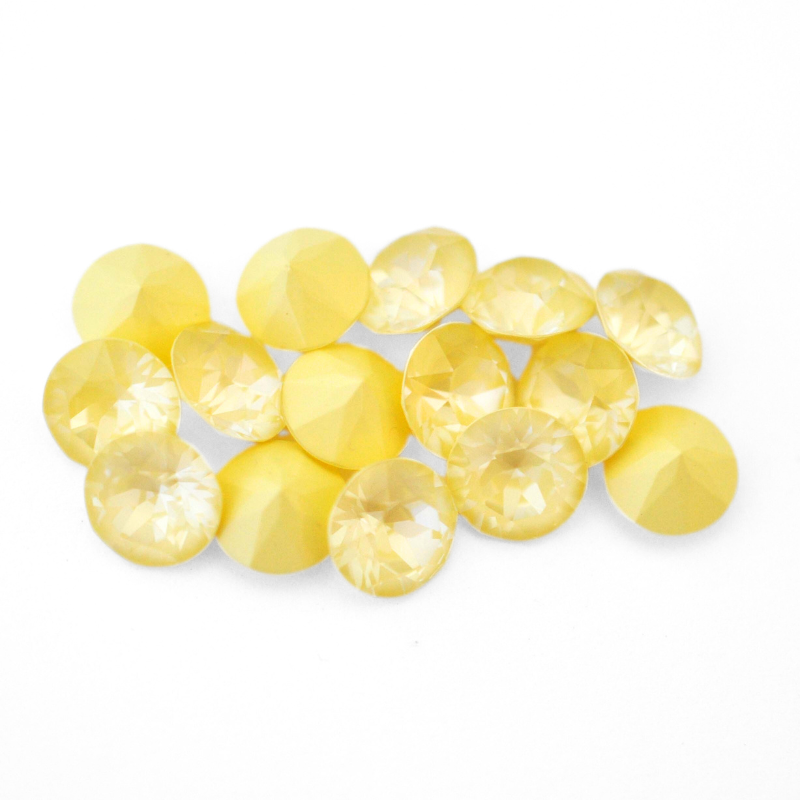 Round faceted Austrian crystal rhinestones in the color Soft Yellow Ignite displayed on a white background.