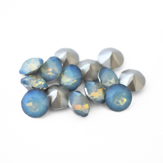 Round faceted Austrian crystal rhinestones in the color White Opal Sky Blue displayed on a white background.