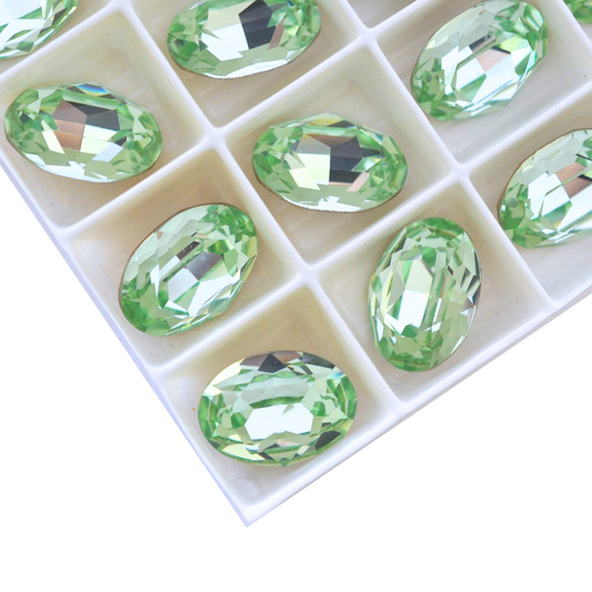 Oval shape faceted Austrian crystal rhinestones in the color Chrysolite displayed on a white background.