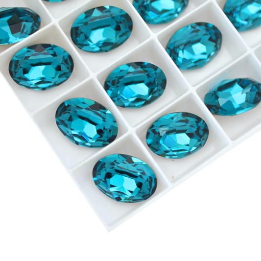 Oval shape faceted Austrian crystal rhinestones in the color Indicolite displayed on a white background.