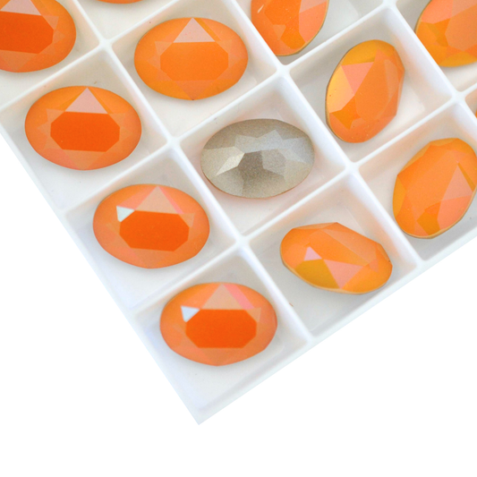 Oval shape faceted Austrian crystal rhinestones in the color Orange Sorbet displayed on a white background.