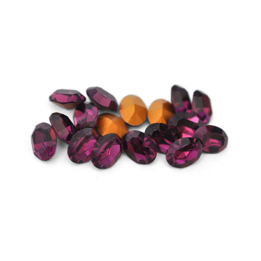 Oval shaped faceted Austrian crystal rhinestones in the color Amethyst displayed on a white background. 