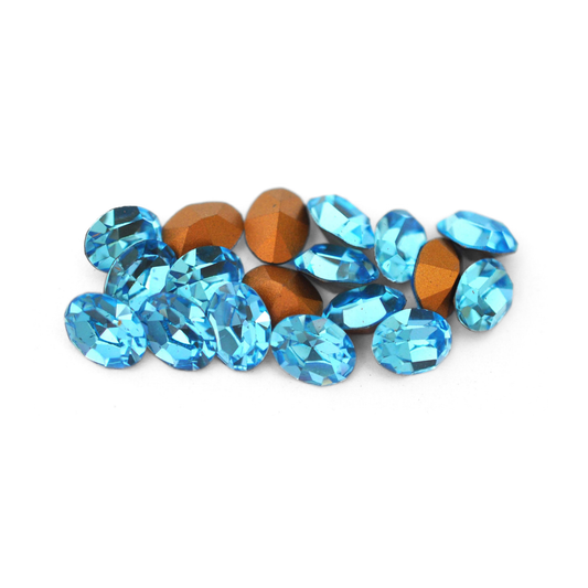Oval shaped faceted Austrian crystal rhinestones in the color Aquamarine displayed on a white background. 