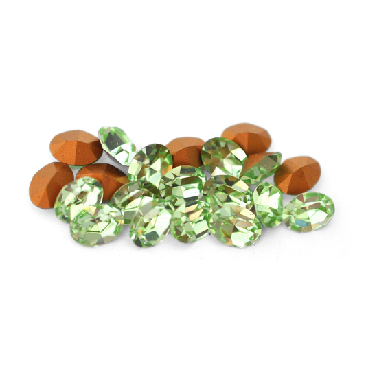 Oval shaped faceted Austrian crystal rhinestones in the color Chrysolite displayed on a white background. 