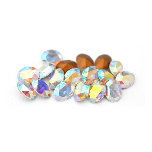 Oval shaped faceted Austrian crystal rhinestones in the color Crystal AB displayed on a white background. 