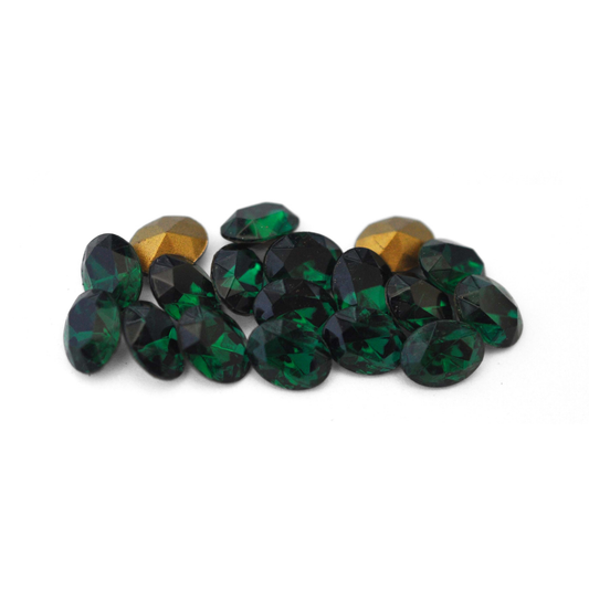 Oval shaped faceted Austrian crystal rhinestones in the color Emerald displayed on a white background. 