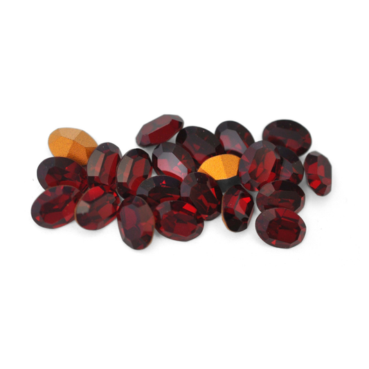 Oval shaped faceted Austrian crystal rhinestones in the color Garnet displayed on a white background. 
