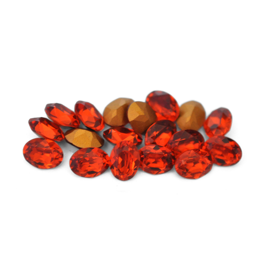 Oval shaped faceted Austrian crystal rhinestones in the color Indian Red displayed on a white background. 