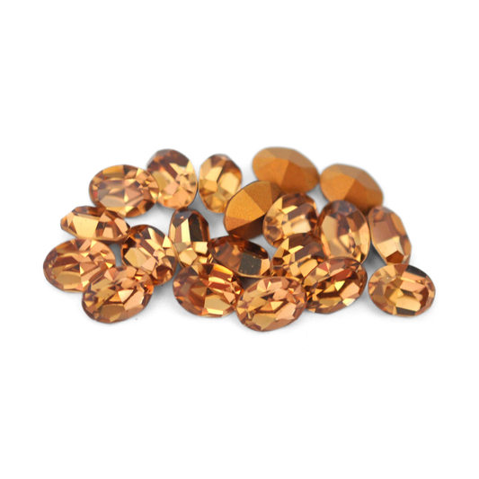 Oval shaped faceted Austrian crystal rhinestones in the color Light Colorado Topaz displayed on a white background. 