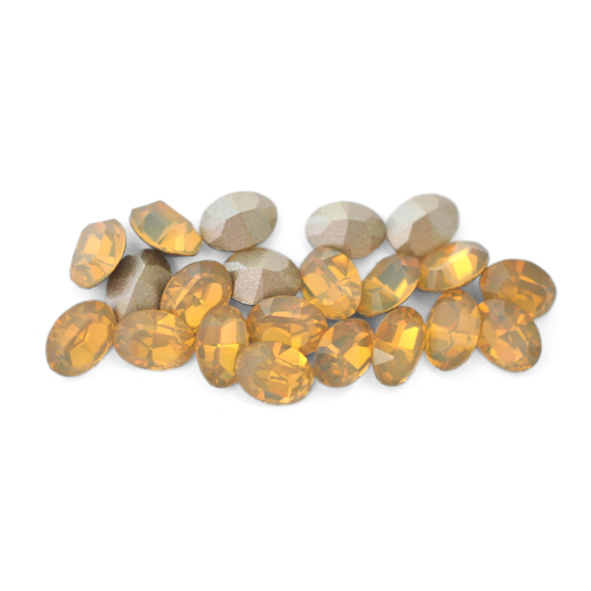 Oval shaped faceted Austrian crystal rhinestones in the color Sand Opal displayed on a white background. 