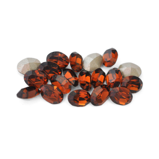 Oval shaped faceted Austrian crystal rhinestones in the color Smoked Topaz displayed on a white background. 