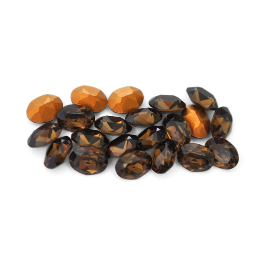 Oval shaped faceted Austrian crystal rhinestones in the color Smoky Quartz displayed on a white background. 