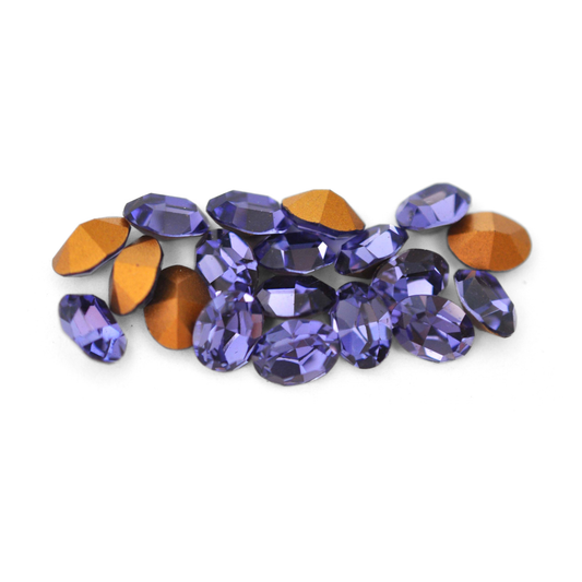 Oval shaped faceted Austrian crystal rhinestones in the color Tanzanite displayed on a white background. 