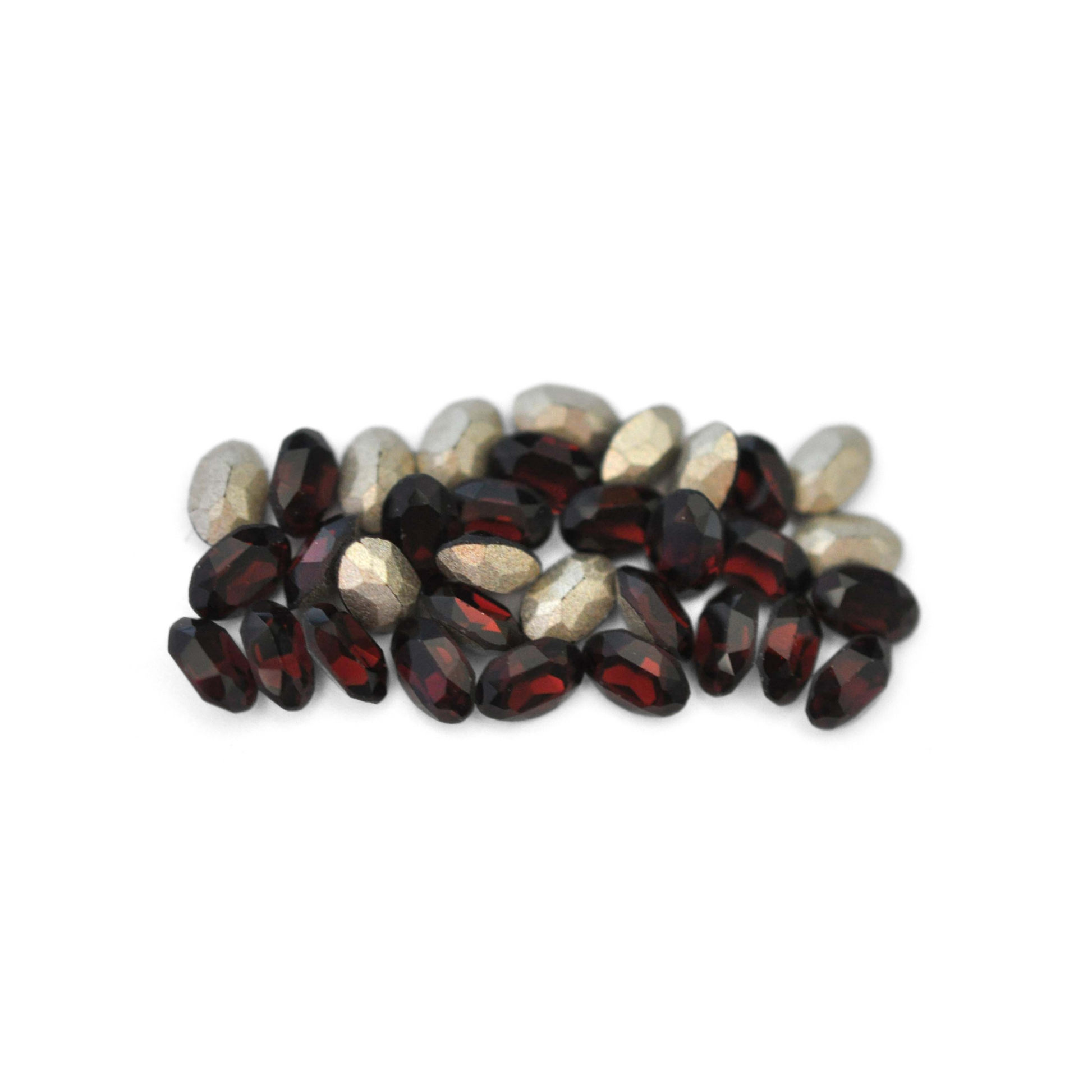 Oval shaped faceted Austrian crystal rhinestones in the color Burgundy displayed on a white background. 