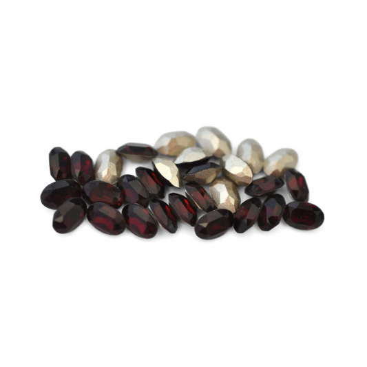 Oval shaped faceted Austrian crystal rhinestones in the color Garnet displayed on a white background. 