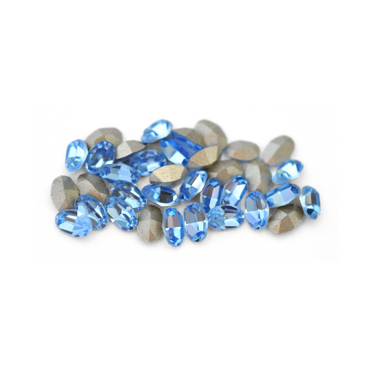 Oval shaped faceted Austrian crystal rhinestones in the color Light Sapphire displayed on a white background. 