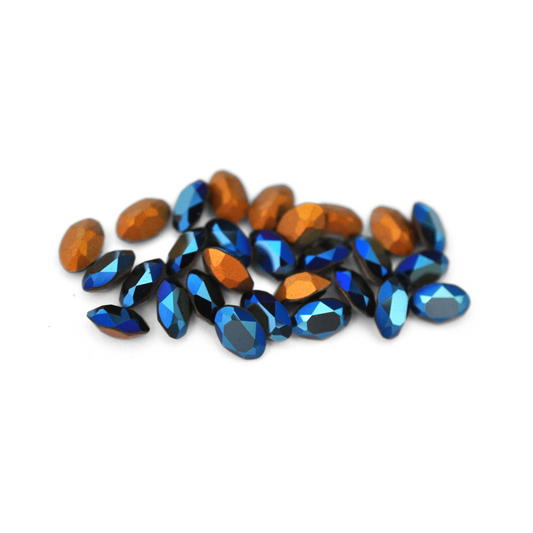 Oval shaped faceted Austrian crystal rhinestones in the color Metallic Blue displayed on a white background. 